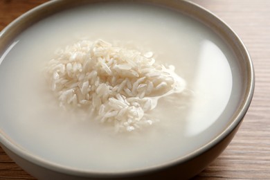 Photo of Rice soaked in water on wooden table, closeup