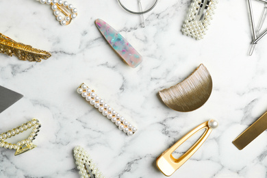 Photo of Stylish hair clips on white marble table, flat lay