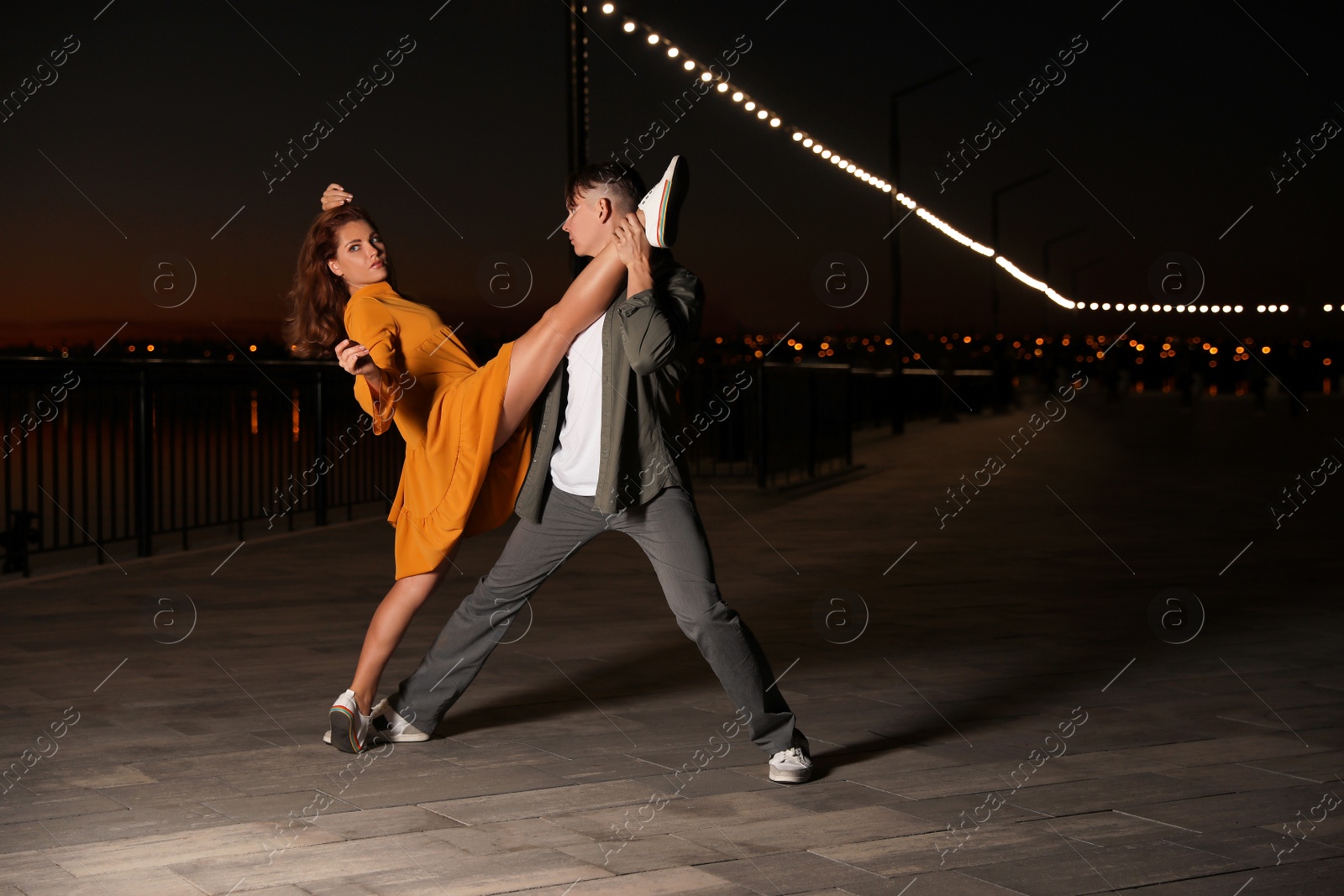 Photo of Beautiful young couple practicing dance moves in evening outdoors