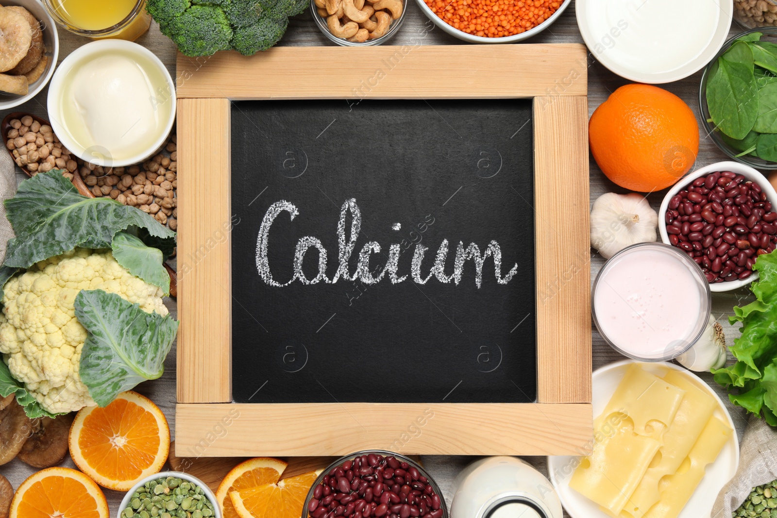 Photo of Set of natural food and chalkboard with written word Calcium on white wooden table, flat lay