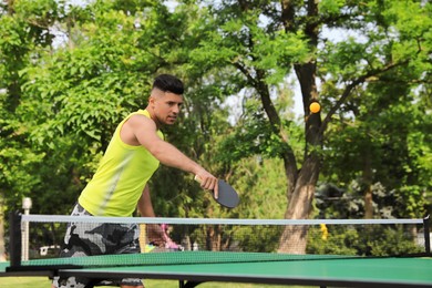Photo of Handsome man playing ping pong outdoors on summer day