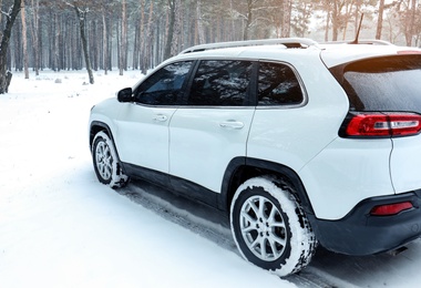 Photo of Modern car on snowy road in forest. Winter season