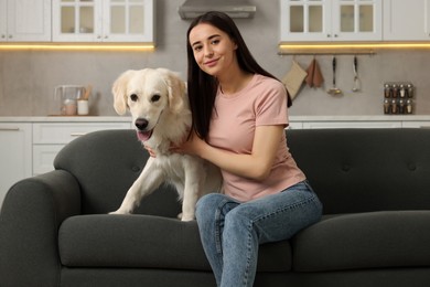 Happy woman with cute Labrador Retriever dog on sofa at home. Adorable pet