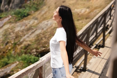 Photo of Feeling freedom. Beautiful woman enjoying nature on wooden bridge in mountains