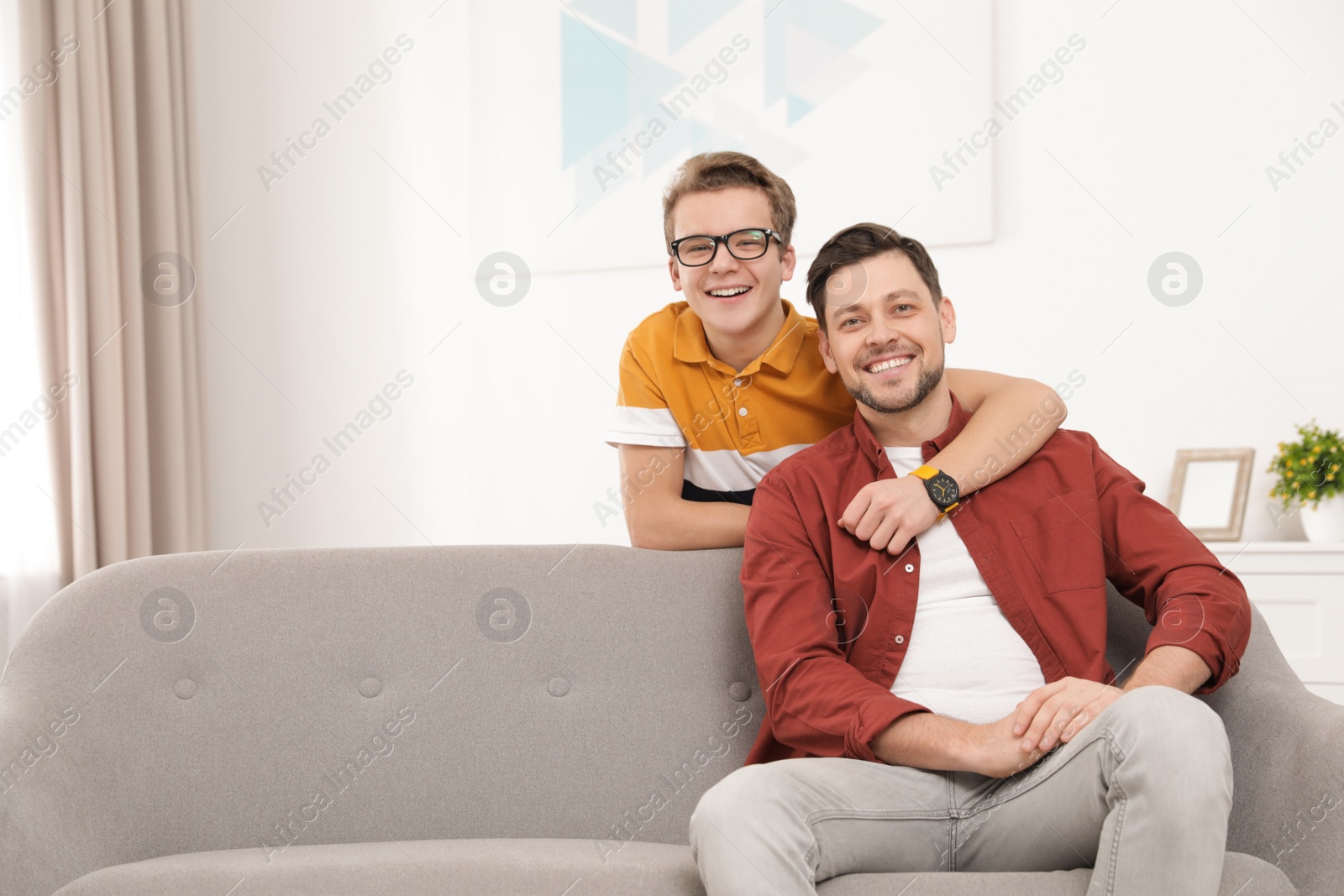 Photo of Happy teenager hugging his father at home. Space for text