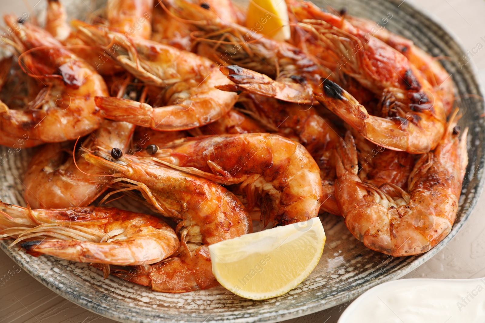 Photo of Delicious cooked shrimps served with lemon on plate, closeup