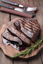 Photo of Delicious grilled beef meat and rosemary served on wooden table, closeup