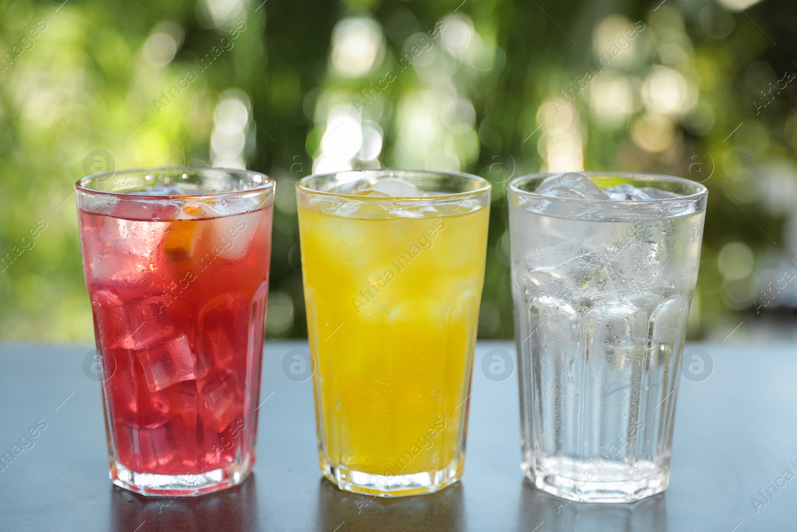 Photo of Delicious refreshing drinks in glasses on grey table outdoors