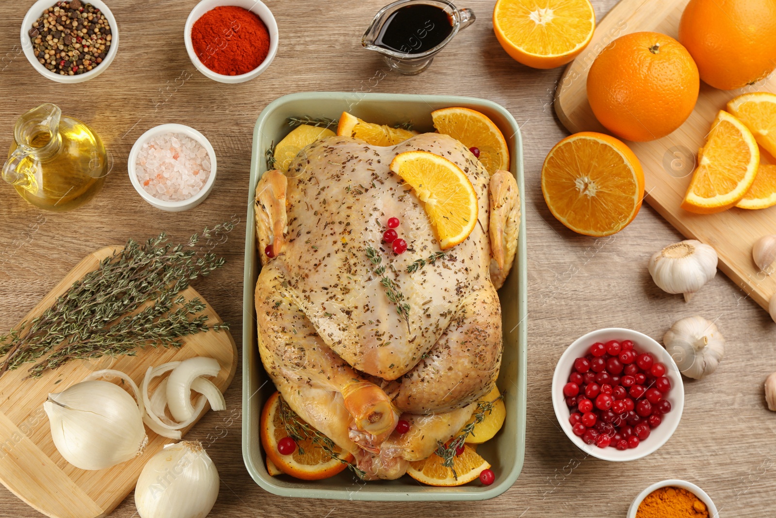 Photo of Raw chicken, orange slices and other ingredients on wooden table, flat lay