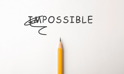 Image of Word IMPOSSIBLE with crossed out letters IM and pencil on white background, top view. Motivation and positivity