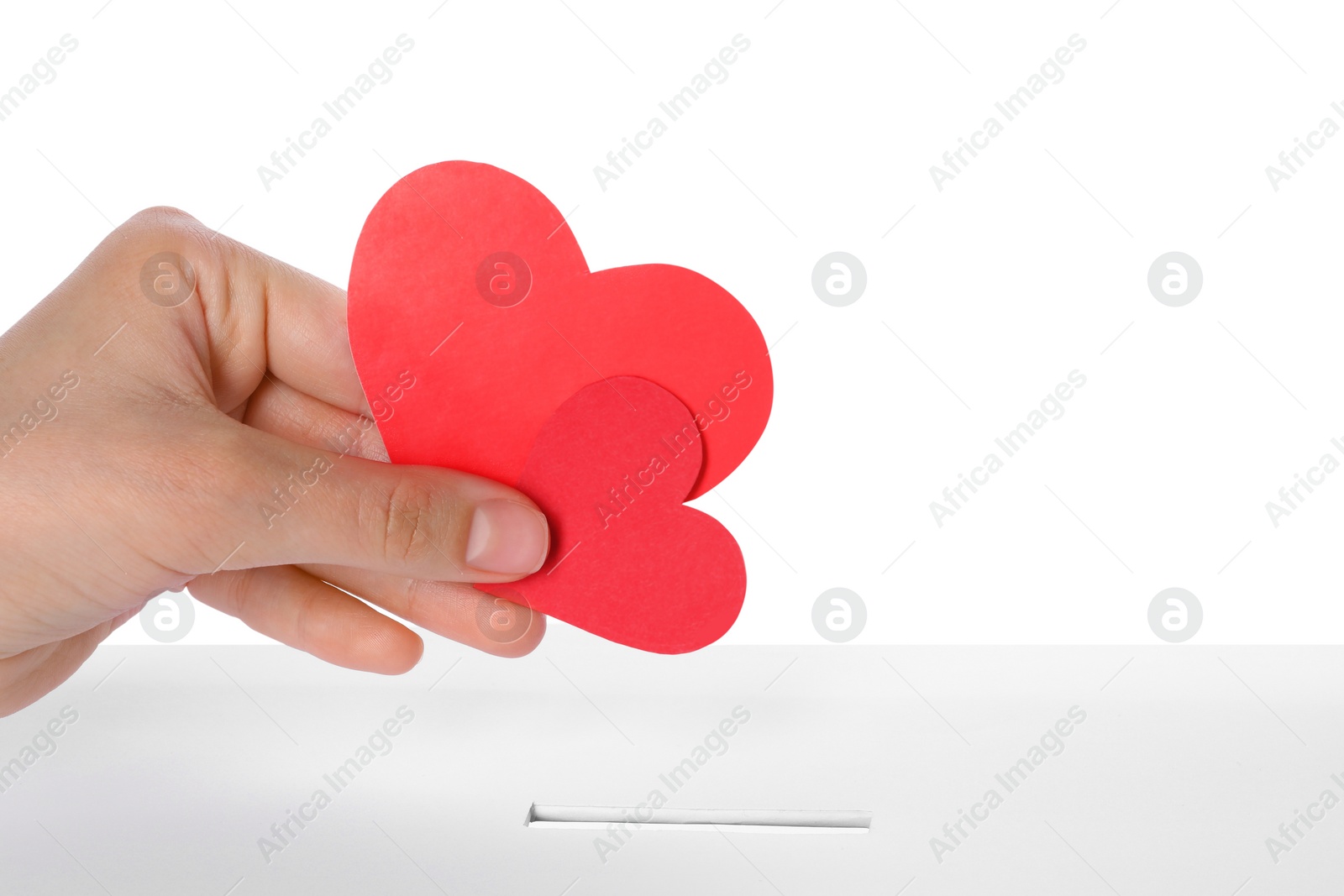 Photo of Woman putting red hearts into slot of donation box against white background, closeup