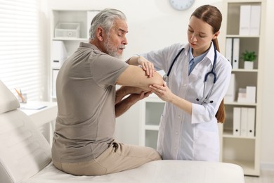 Photo of Arthritis symptoms. Doctor examining patient's elbow in hospital