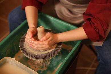 Photo of Woman crafting with clay on potter's wheel, closeup