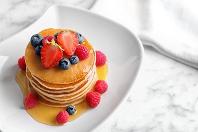 Tasty pancakes with berries and honey on plate