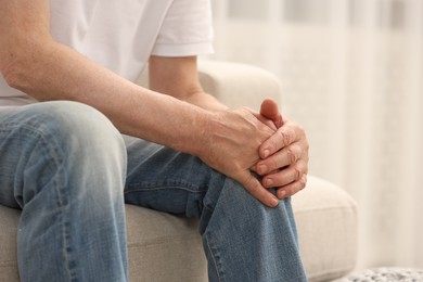 Senior man suffering from pain in leg indoors, closeup. Rheumatism symptom