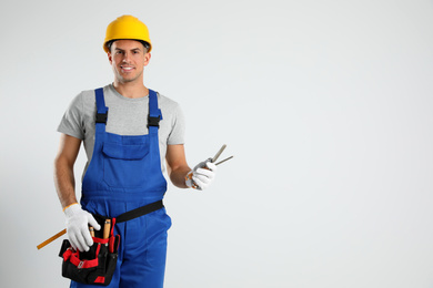Photo of Carpenter with tool belt and chisels on light background. Space for text