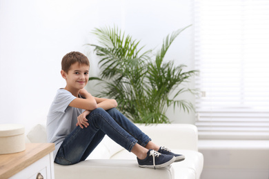 Photo of Cute little boy sitting in living room
