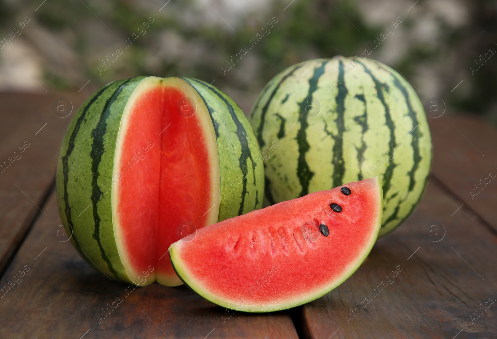 Photo of Delicious cut and whole ripe watermelons on wooden table
