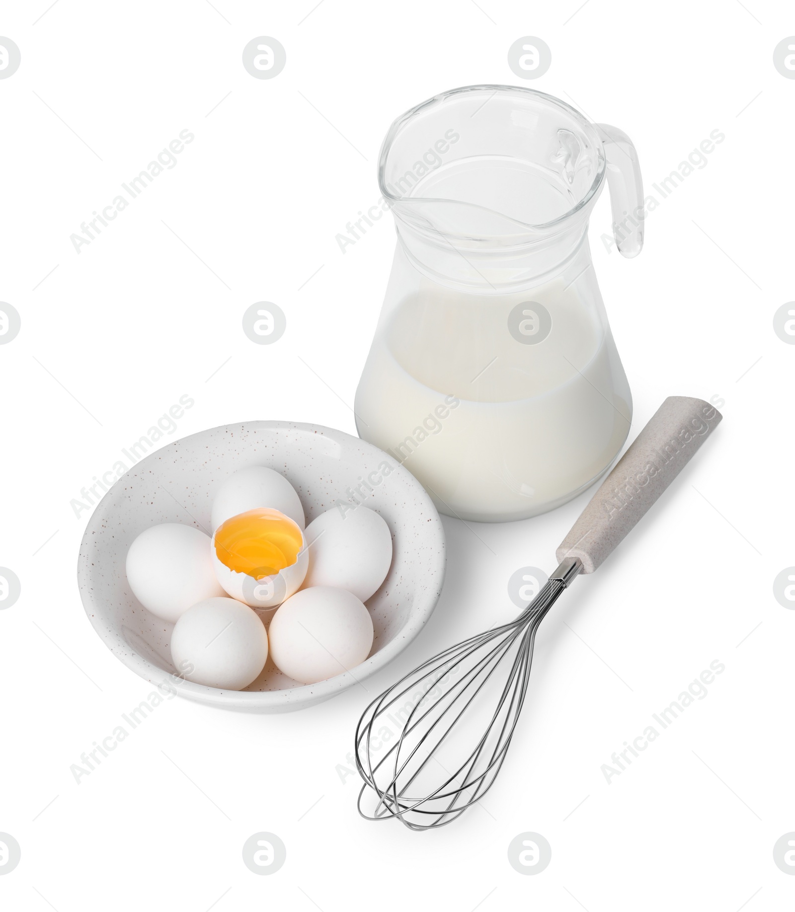 Photo of Whisk, raw eggs and jug of milk isolated on white, above view