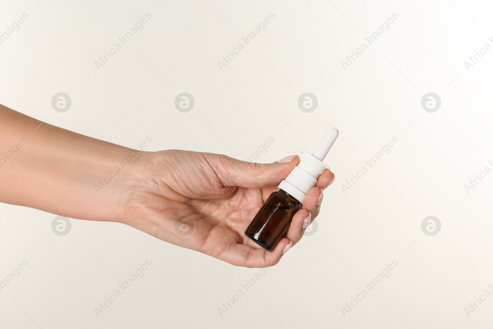 Photo of Woman holding nasal spray on white background, closeup