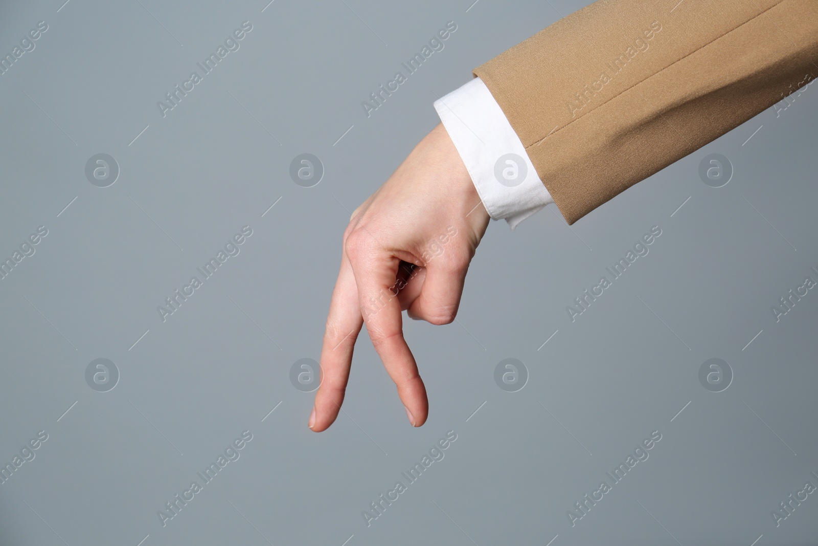 Photo of Businesswoman imitating walk with hand on grey background, closeup. Finger gesture