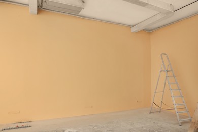 Photo of Ladder near pale orange wall, space for text. Room renovation