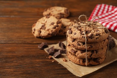 Photo of Many delicious chocolate chip cookies on wooden table. Space for text
