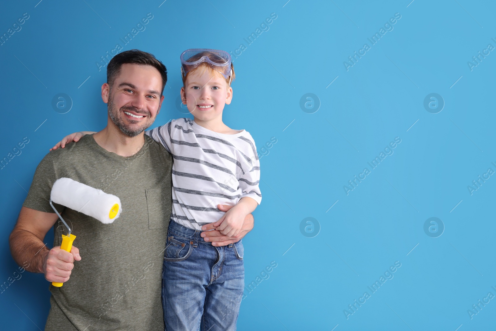 Photo of Father and son with roller near blue wall, space for text. Repair work