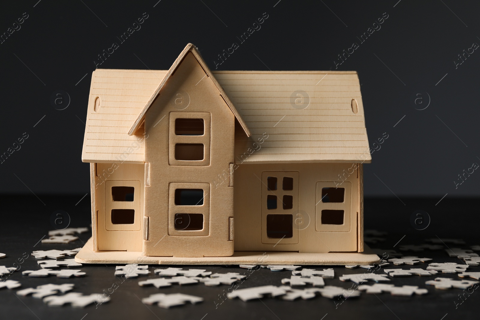 Photo of House model and puzzles on black table depicting destruction after earthquake