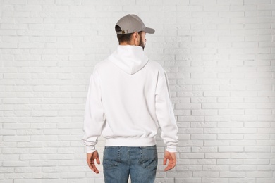 Young man in sweater at brick wall. Mock up for design