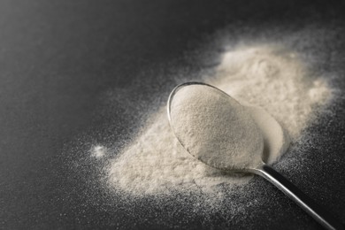 Photo of Spoon of agar-agar powder on black background, closeup. Space for text