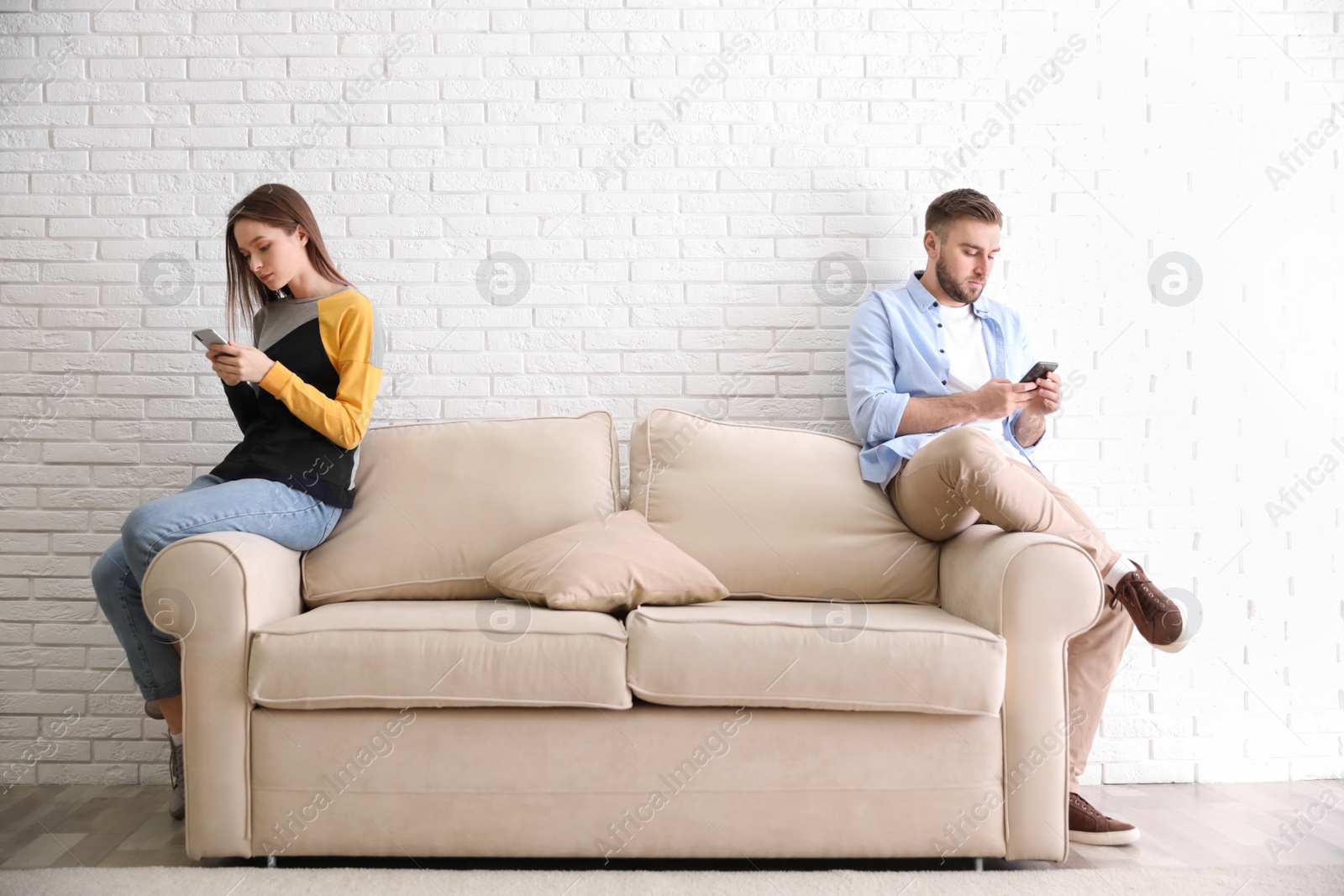 Photo of Couple addicted to smartphones ignoring each other at home. Relationship problems