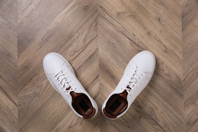 Pair of stylish sports shoes on wooden floor, top view