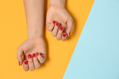 Woman showing red manicure on color background, top view with space for text. Nail polish trends