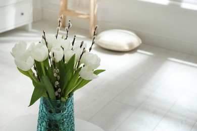 Beautiful bouquet of willow branches and tulips in vase indoors, space for text