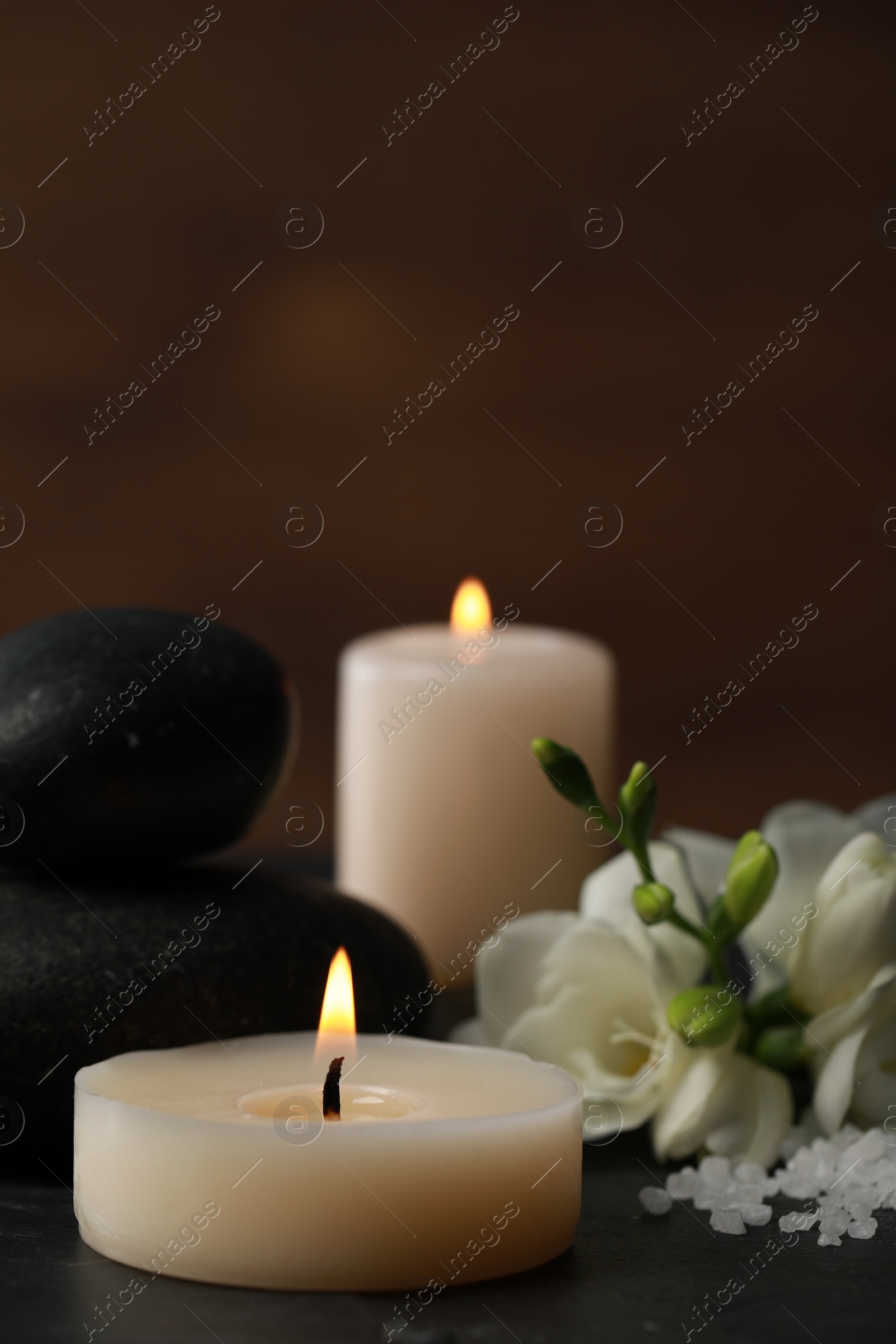 Photo of Beautiful composition with spa stones, burning candles and flowers on black table