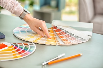 Female designer working with color palette samples at table