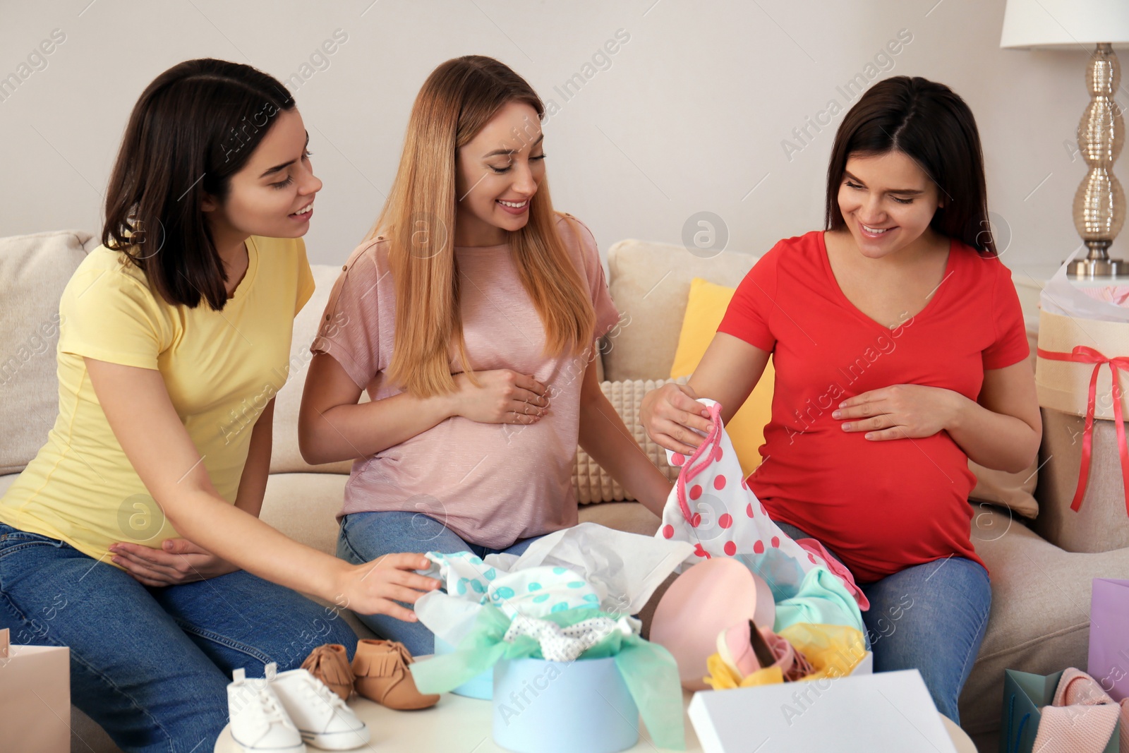 Photo of Happy pregnant women spending time together in living room after shopping