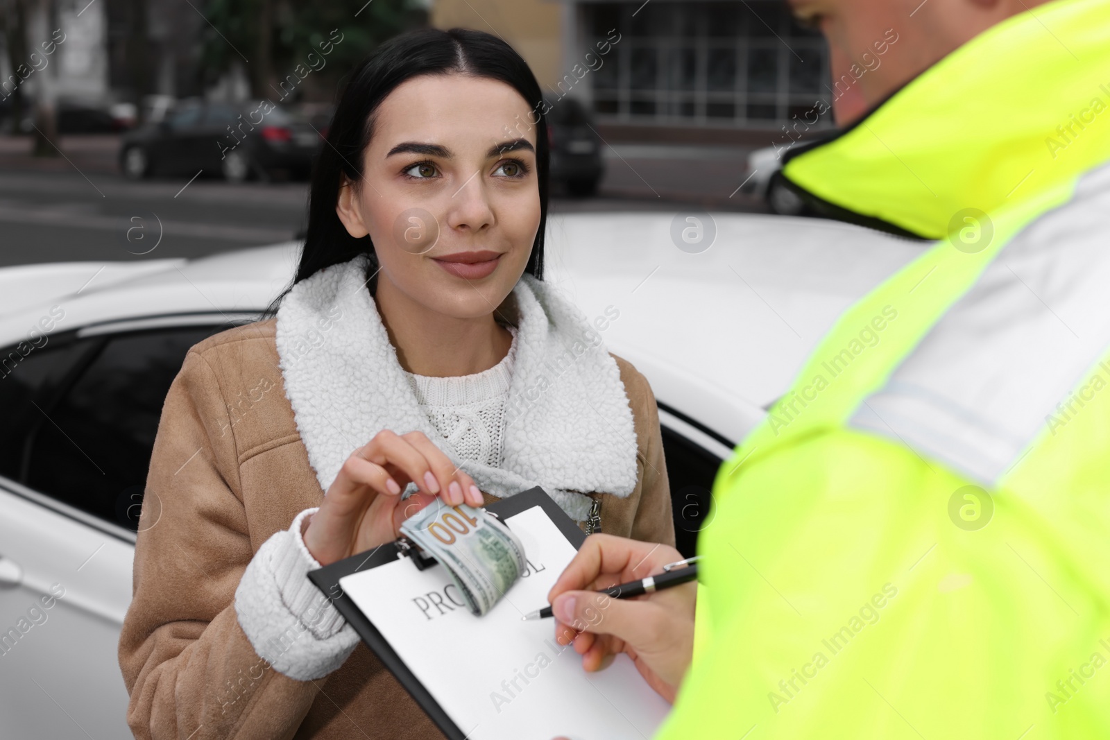 Photo of Woman giving bribe to police officer near car outdoors