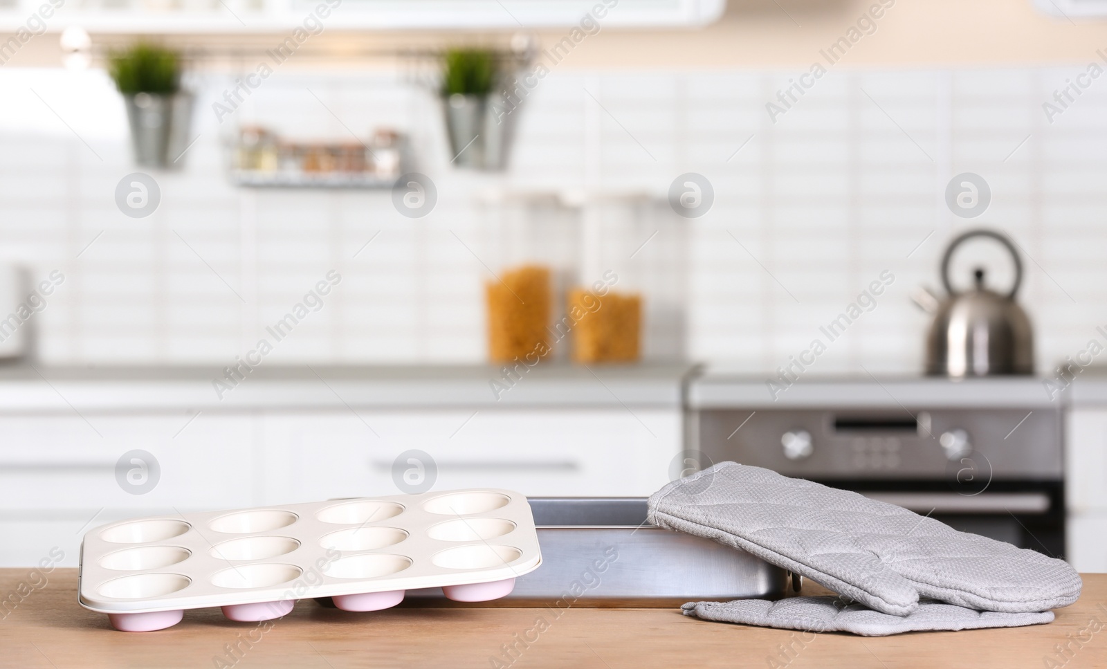 Photo of Clean baking dish, muffin pan and oven glove on table in kitchen. Space for text