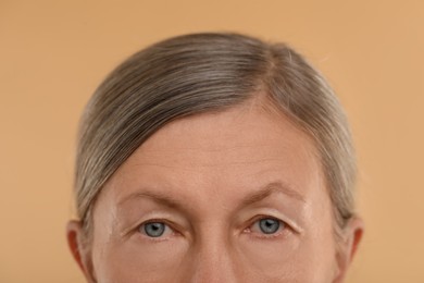 Woman with beautiful eyes on beige background, macro view