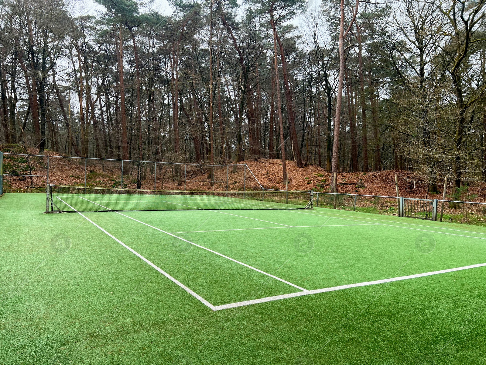 Photo of Tennis court with artificial grass and net outdoors