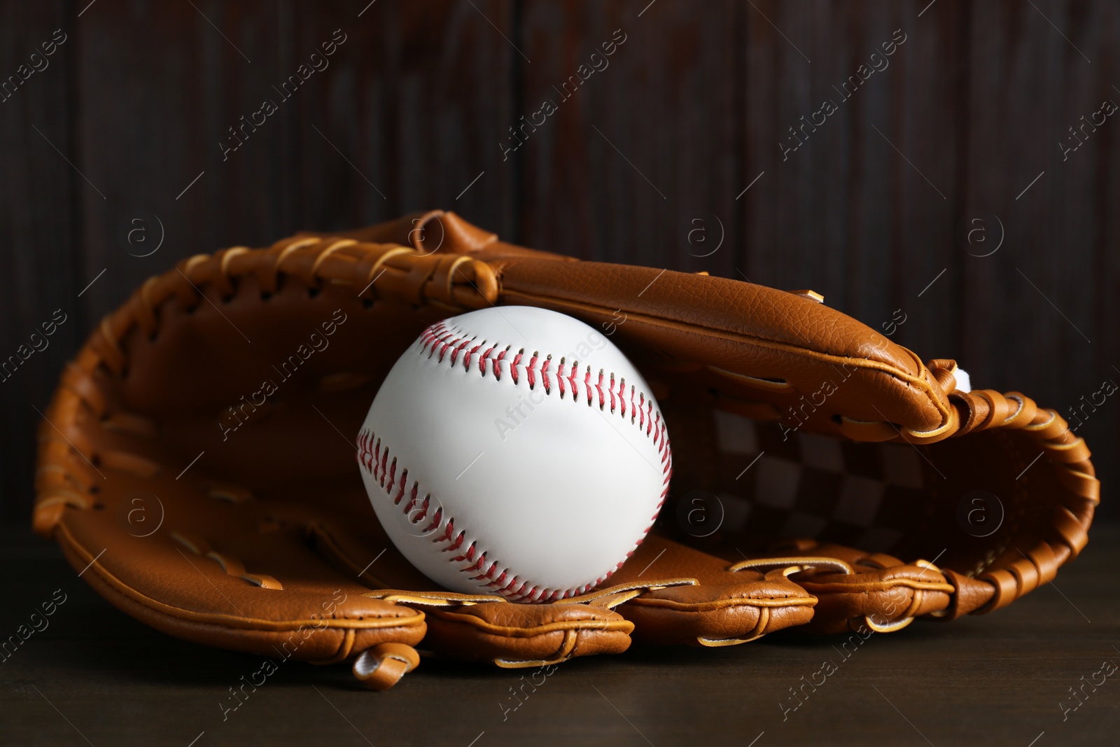 Photo of Leather baseball glove with ball on wooden table