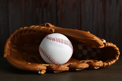Photo of Leather baseball glove with ball on wooden table