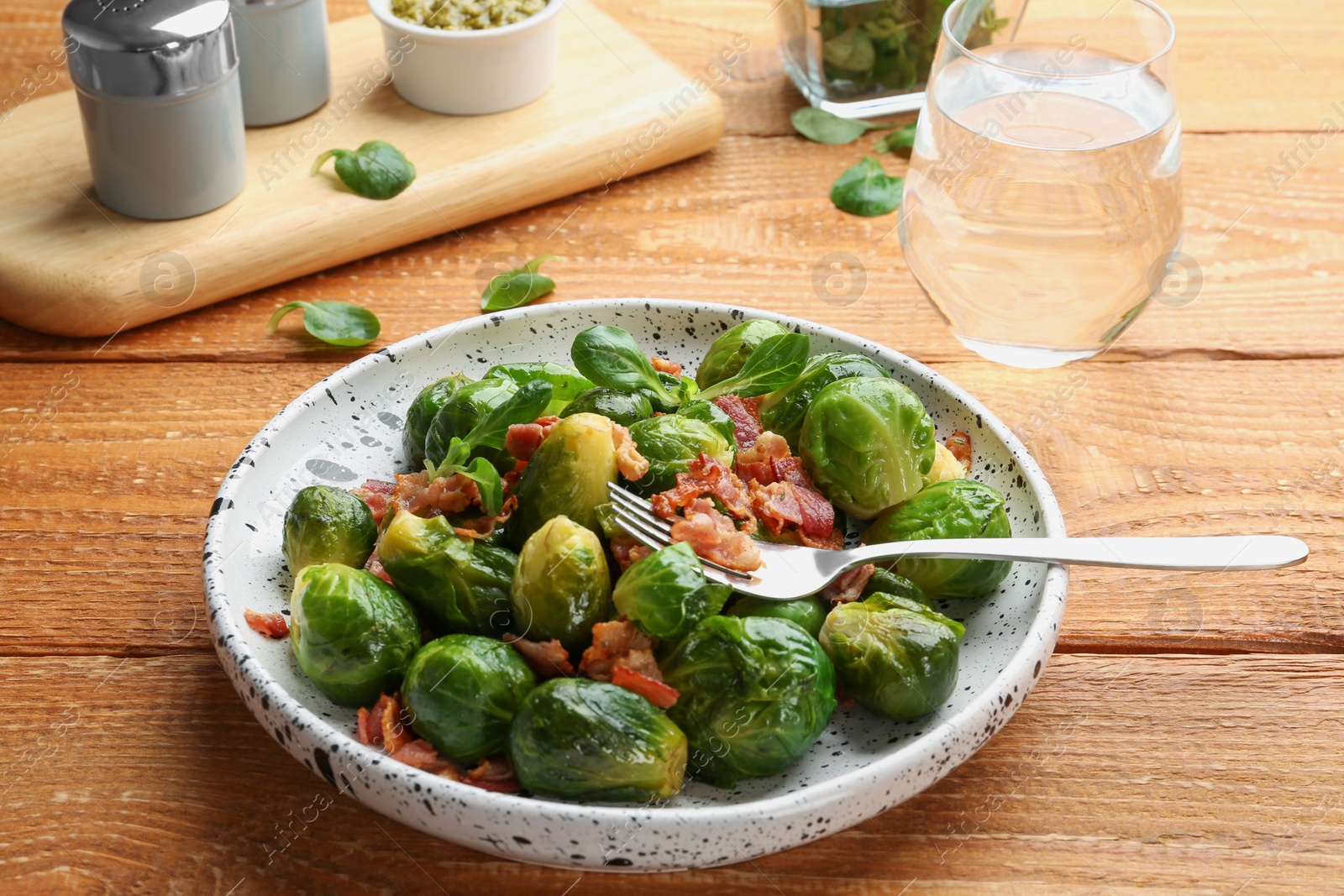 Photo of Tasty roasted Brussels sprouts with bacon on wooden table