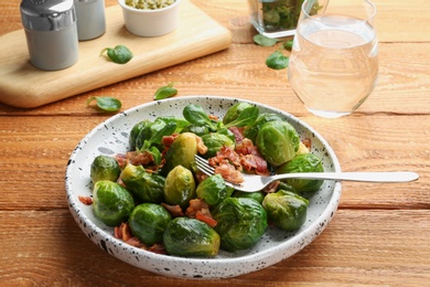 Tasty roasted Brussels sprouts with bacon on wooden table