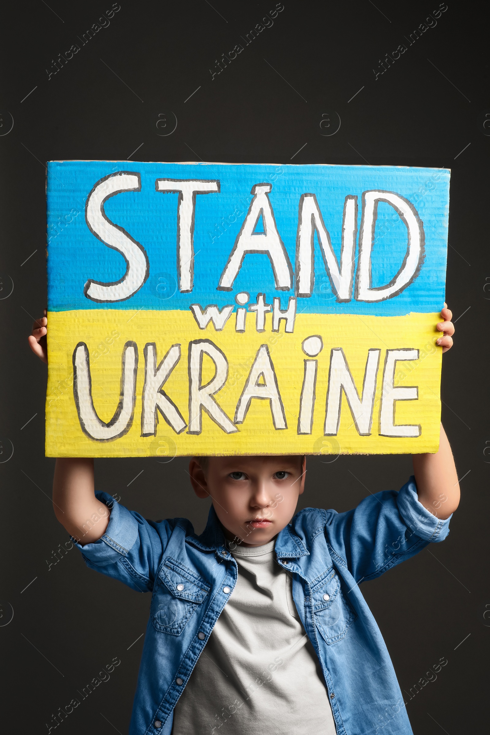 Photo of Boy holding poster Stand with Ukraine against grey background