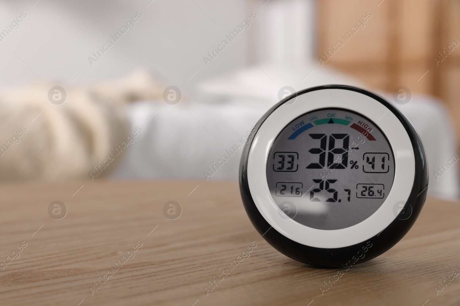 Photo of Digital hygrometer with thermometer on wooden table indoors. Space for text