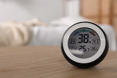 Digital hygrometer with thermometer on wooden table indoors. Space for text