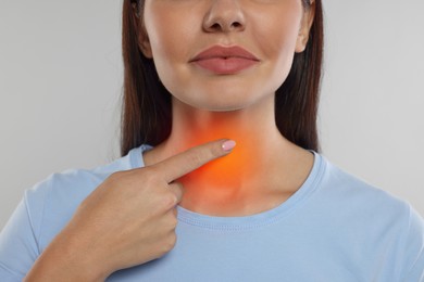 Image of Endocrine system. Woman doing thyroid self examination on light grey background, closeup